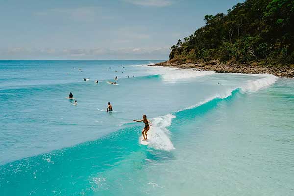 Surfer in the turquoise water of the beaches at Noosa National Park on a summers day.